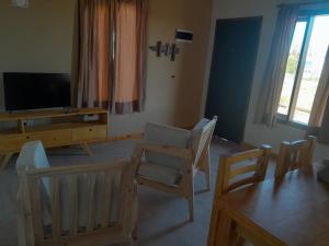 ein Wohnzimmer mit Stühlen, einem TV und einem Tisch in der Unterkunft Elegante cabaña. in El Calafate