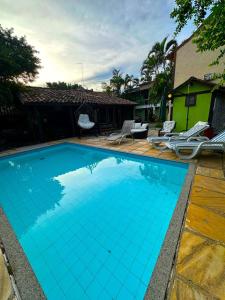 布希奧斯的住宿－Repouso das Flores，一个带椅子的蓝色游泳池以及一座房子