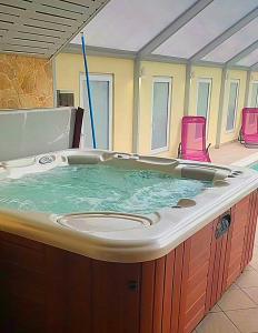 a large hot tub in a room with pink chairs at D&P WELLNESSHÁZ in Dabas