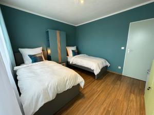 a bedroom with two beds with blue walls and wooden floors at JUNX Bude in Marl