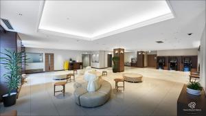 a lobby with a couch and tables and chairs at Daiwa Roynet Hotel Hachinohe in Hachinohe