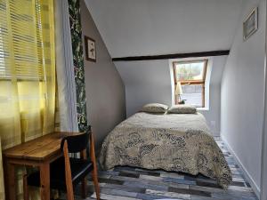 Schlafzimmer mit einem Bett, einem Schreibtisch und einem Fenster in der Unterkunft Appartement du haut 1 in Cordemais