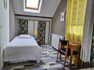 a bedroom with a bed and a desk and a window at Appartement du haut 1 in Cordemais