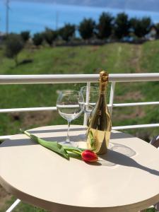 a white table with a bottle of wine and a flower at Ions seaview apartments in Vlorë