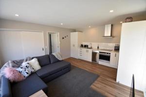 a living room with a blue couch and a kitchen at Twin Rivers Spa Retreat in Queenstown