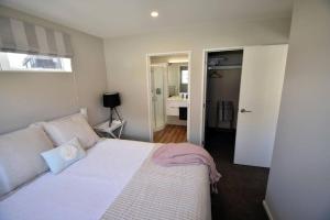 a bedroom with a white bed and a bathroom at Twin Rivers Spa Retreat in Queenstown