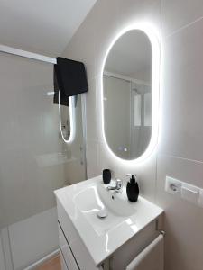 Baño blanco con lavabo y espejo en Casa Rural La Escapadita en Benaoján