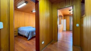 a hallway with a bed in a room with wooden walls at Dúplex Jaguaribe in Campos do Jordão