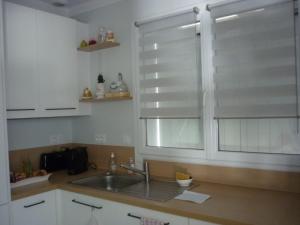 een keuken met een wastafel en een raam met jaloezieën bij maison 20mn de la mer in Aigrefeuille-dʼAunis