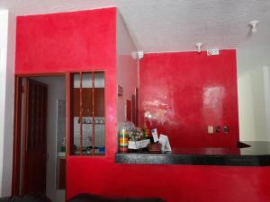 a kitchen with a red wall and a red cabinet at Hotel Daylin in Aguachica