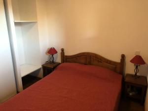 1 dormitorio con 1 cama roja y 2 lámparas en las mesas en Résidence Hameau De Balestas Mp - 3 Pièces pour 6 Personnes 171, en Germ