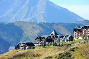 a resort on a hill with a mountain in the background at Résidence Hameau De Balestas Mp - T3/6pers JOUBARDE 01- Peyresourde MAE-1171 in Germ