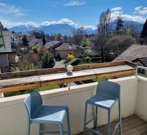 two chairs on a balcony with a view of mountains at Calme à 2 pas du lac 3 chambres in Annecy