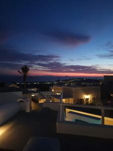 a night view of a building with a palm tree at Astivi Santorini Apartments in Pirgos