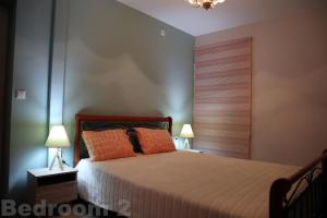 um quarto com uma cama com almofadas laranja e 2 candeeiros em Cosy Beach House in Agios Vasilios, Patras em Áyios Vasílios