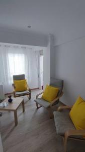 uma sala de estar com 2 cadeiras e almofadas amarelas em Apartamento en Inferniño Ferrol em Ferrol