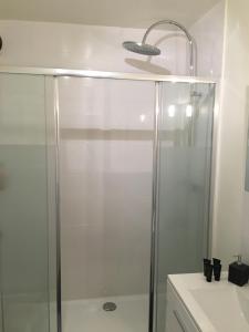 une douche avec une porte vitrée dans une salle de bain dans l'établissement Grand Studio design avec parking, à Neuilly-sur-Seine