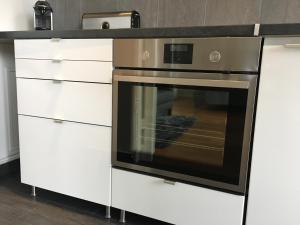 Il comprend une cuisine équipée d'une cuisinière et de placards blancs. dans l'établissement Grand Studio design avec parking, à Neuilly-sur-Seine