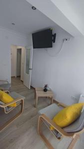 uma sala de estar com duas cadeiras e uma televisão na parede em Apartamento en Inferniño Ferrol em Ferrol