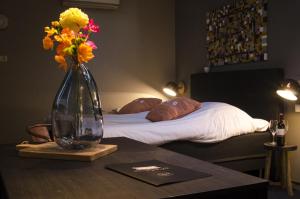 烏登的住宿－讓邦酒店，花瓶坐在床边的桌子上