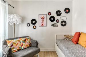 a living room with a couch and records on the wall at Studio Pop plein Centre-Port - ménage, linge inclus in Cap d'Agde +14 photos