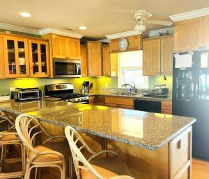 a kitchen with a large counter with chairs in it at Clamelot in Holden Beach