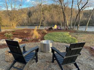 two chairs sitting on a gravel patio next to a lake at Asheville River Cabins in Arden