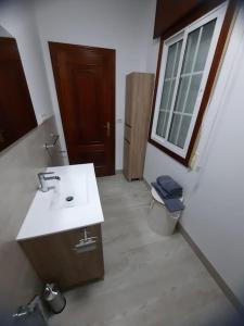 a bathroom with a sink and a toilet and a window at Fogar dos Petellos, Mondariz. in Mondariz
