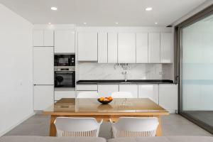 a kitchen with a wooden table and white cabinets at Gaivota Ocean view & 5min walk beach in Luz