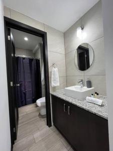 a bathroom with a sink and a toilet and a mirror at Senua - Moderno y artistico apartamento in Guatemala