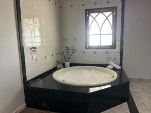 een groot bad in een badkamer met een raam bij POUSADA BELLA CANASTRA in Piuí