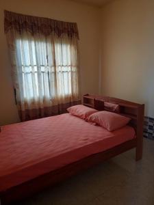 a bedroom with a bed with red sheets and a window at Kapowlito Real Estate Casa Sitalweg in Paramaribo