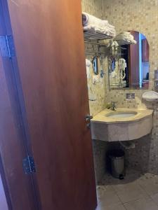 La salle de bains est pourvue d'un lavabo et d'une porte en bois. dans l'établissement فندق ليمة الفضية - Leema Al Fadya Hotel, à La Mecque