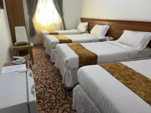 a row of four beds in a hotel room at فندق ليمة الفضية - Leema Al Fadya Hotel in Makkah