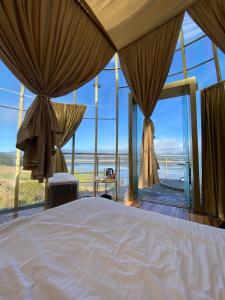 Guatavita Glamping club في بوغوتا: غرفة نوم مع سرير وإطلالة على المحيط
