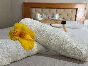 a towel on a bed with a yellow flower on it at POUSADA BELLA CANASTRA in Piumhi