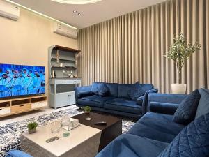 sala de estar con sofás azules y TV en شقة فاخرة غرفة وصالة بالعارض ٢ en Riad