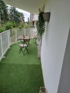 un patio con césped verde, mesa y sillas en Allée des cedres, en Villepinte