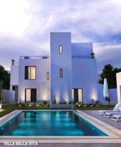 a white house with a swimming pool in front of it at VILLA BELLA VITA HAMMAMET in Hammamet Sud