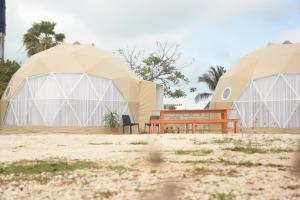 duas tendas abobadadas com um banco no deserto em Hidden Island Glamping Isla Mujeres em Ilha das Mulheres