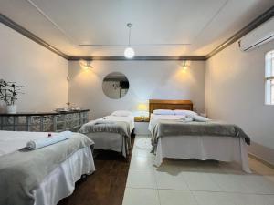 a room with three beds and a mirror at POUSADA BELLA CANASTRA in Piumhi