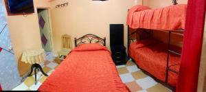 um quarto com 2 beliches e lençóis vermelhos em HOTEL ORO BLANCO em Uyuni