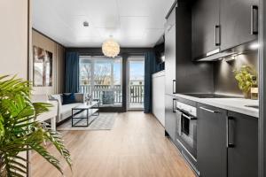 a kitchen with black cabinets and a living room at Studioleilighet, uten soverom in Bodø