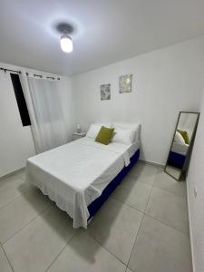 - une chambre avec un lit blanc et un miroir dans l'établissement Alojamiento en San Juan Opico, à San Juan Opico