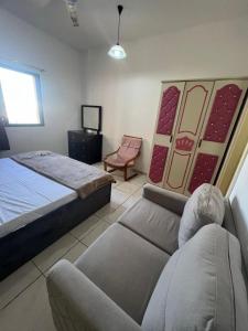1 dormitorio con 1 cama, 1 sofá y 1 silla en Seaside master bedroom, en Sharjah