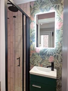 uma casa de banho com um lavatório e um chuveiro com um espelho. em The Holiday House - Portstewart em Portstewart