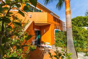 ein orangefarbenes Gebäude mit einem Tisch und einer Palme in der Unterkunft Casas Novas Guesthouse - Adults Only in Lagos