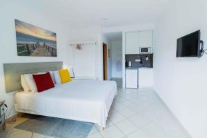 Casas Novas Guesthouse - Adults Only في لاغوس: غرفة نوم بيضاء مع سرير أبيض ومطبخ