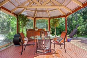 un patio con una mesa de cristal y sillas en una terraza de madera en Ballarat Cottages en Ballarat