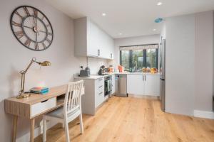 a kitchen with a desk and a clock on the wall at Two-bedroom flat near Wembley, London in Wealdstone